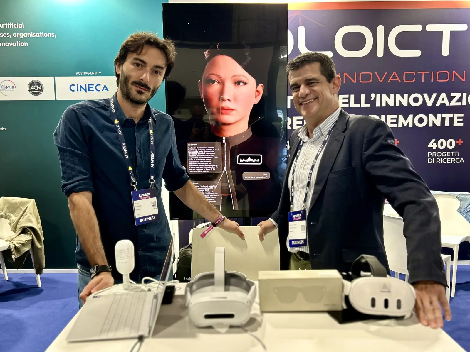 Guido D'Arezzo and Francisco Javier Alonso Peña at the DeuSens booth at AI Week 2026 with Alice Assistant avatar and VR headsets