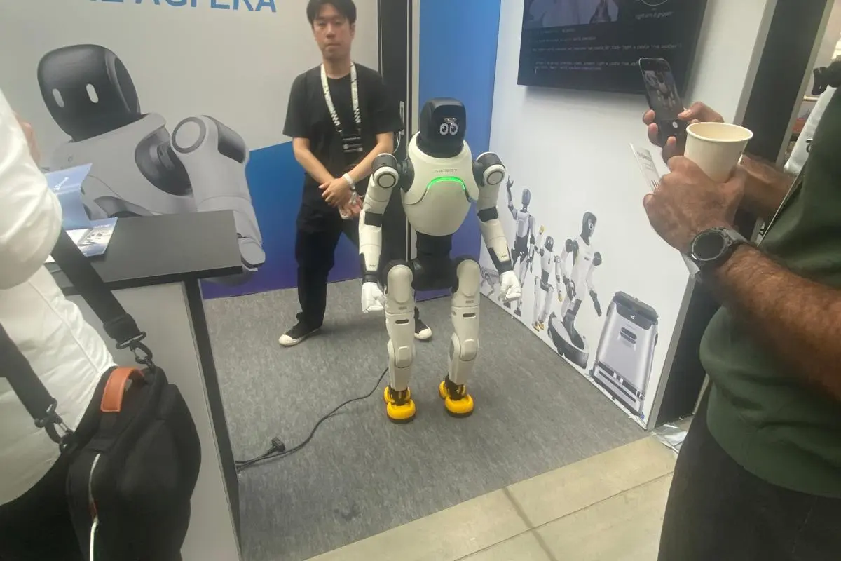 Humanoid robot among attendees on the MACHINA Summit 2026 exhibition floor